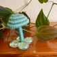 sage green mushroom collectible Made with sage green yarn wrapped around rope and shaped into a mushroom with  glass stone platform for standing, perfect for mushroom lovers and or collectors, can also be used as an ornament (hook is included in order)  Materials: acrylic yarn, rope, hot glue