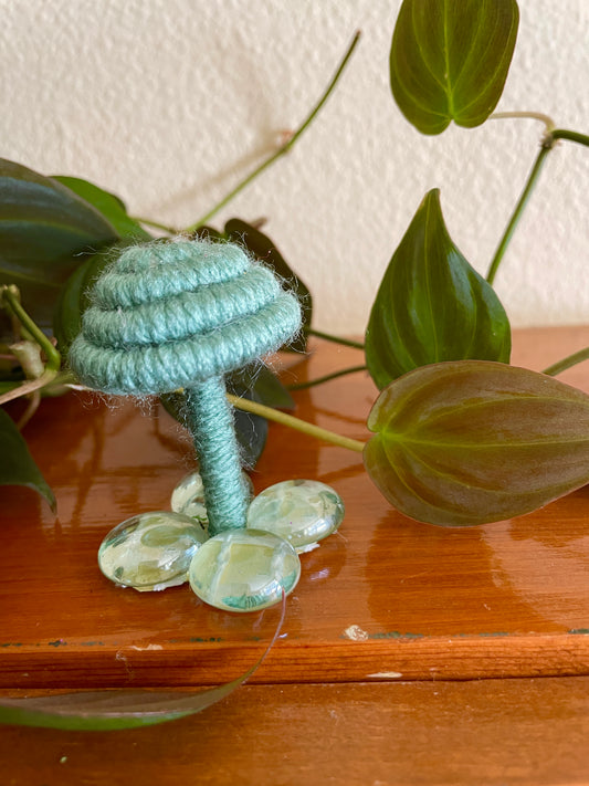 sage green mushroom collectible Made with sage green yarn wrapped around rope and shaped into a mushroom with  glass stone platform for standing, perfect for mushroom lovers and or collectors, can also be used as an ornament (hook is included in order)  Materials: acrylic yarn, rope, hot glue