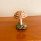 raffia mushroom collectible Made with raffia paper wrapped around rope and shaped into a mushroom with small flat platform adorned with rocks and moss for standing, perfect for mushroom lovers and or collectors, can also be used as an ornament (hook is included in order)  Materials: acrylic yarn, rope, hot glue  Dimensions: