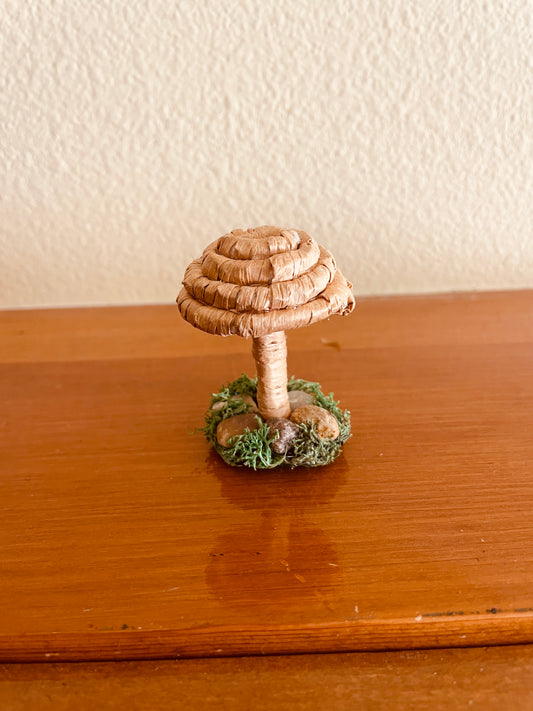 raffia mushroom collectible Made with raffia paper wrapped around rope and shaped into a mushroom with small flat platform adorned with rocks and moss for standing, perfect for mushroom lovers and or collectors, can also be used as an ornament (hook is included in order)  Materials: acrylic yarn, rope, hot glue  Dimensions:
