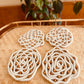 Very unique coaster set made with cream yarn wrapped rope with brown wood beads embedded throughout for a lattice pattern.  Materials: acrylic yarn, rope, wood beads, hot glue, felt fabric (on bottom)