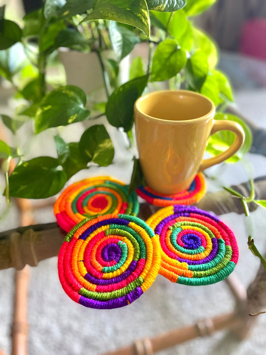 rainbow coaster set Bright and bold coaster set made with yarn wrapped on thin rope, includes colors orange, purple, pink, blue, yellow, and green. Comes in a set of 4  Materials: Yarn,  rope, hot glue